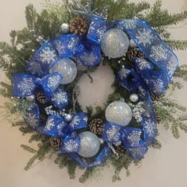 Christmas wreath with blue ribbon, silver ornaments, and pinecones