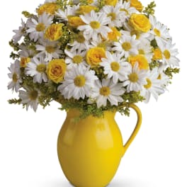 Yellow pitcher vase filled with white daisies and yellow roses
