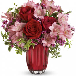 Red roses and pink lilies arranged in a red glass vase