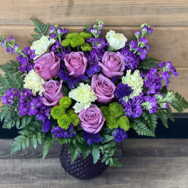 Bouquet of pink roses, purple flowers, and green mums in a dark vase