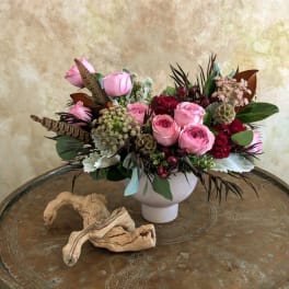Pink rose arrangement in a white vase with mixed foliage and berries