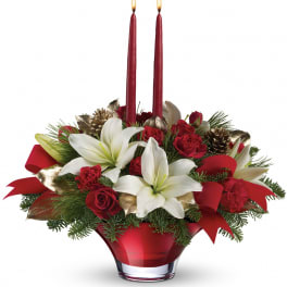 Red and white floral centerpiece with two red candles in a glass vase