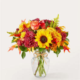 Fall bouquet of sunflowers, roses, and mums in a clear glass vase