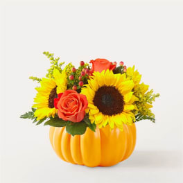 Sunflowers and orange roses arranged in a pumpkin-shaped container