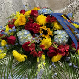 Large mixed flower arrangement with red roses, yellow mums, and blue hydrangeas