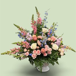 Large pastel bouquet with roses, snapdragons, and blue flowers in a vase