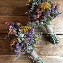 Two rustic hand-tied bouquets with purple, yellow, and pink dried flowers