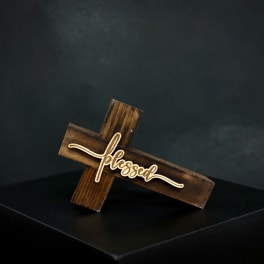Wooden cross sign with the word blessed on a dark pedestal