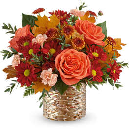 Autumn bouquet of orange roses and red daisies in a gold vase