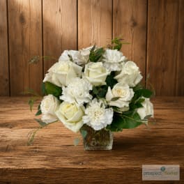 White rose and carnation bouquet in a clear glass vase