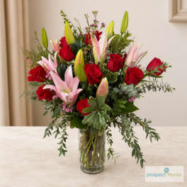 Red roses and pink lilies arranged in a clear glass vase