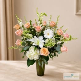 Peach roses and white lilies in a tall glass vase
