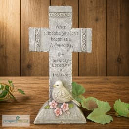 Decorative memorial cross with a bird and pink flowers on a wooden surface