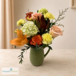 Mixed bouquet of roses, lilies, hydrangeas, and carnations in a green vase