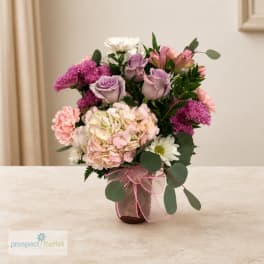 Mixed pink and lavender bouquet in a glass vase with a ribbon