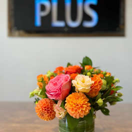 Orange and pink flowers arranged in a glass vase
