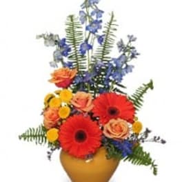 Colorful bouquet in a gold vase with red gerberas and blue flowers