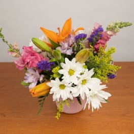 Mixed bouquet in a pink vase with orange lilies and white daisies
