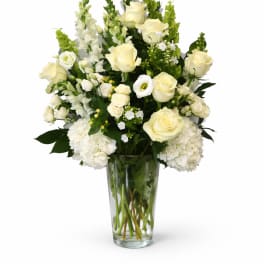 White roses and hydrangeas arranged in a clear glass vase
