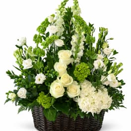 White roses and green flowers arranged in a wicker basket