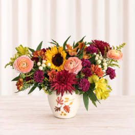 Mixed bouquet of bright flowers in a white ceramic vase