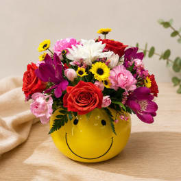 Mixed bouquet in a yellow smiley-face vase
