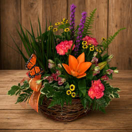 Mixed floral basket with orange lily, pink blooms, and a butterfly accent