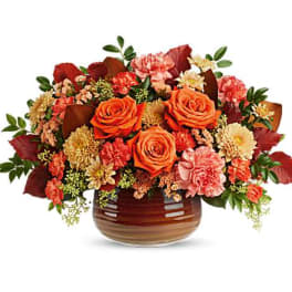 Orange roses and pink carnations in a brown glass vase