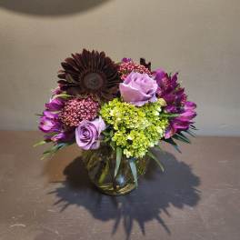 Purple and green mixed bouquet in a glass vase