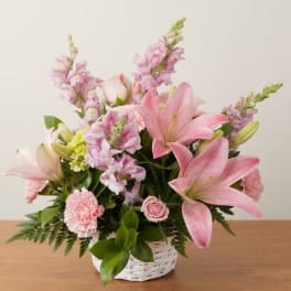 Pink lilies and mixed pastel flowers arranged in a white basket