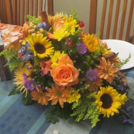 Mixed bouquet with sunflowers, orange roses, and purple flowers on a table