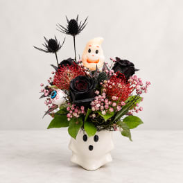 Halloween floral arrangement in a ghost-shaped vase with black and red flowers