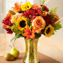 Mixed bouquet of roses, sunflowers, and lilies in a gold vase