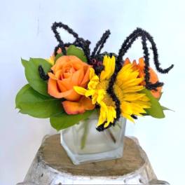 Orange rose and yellow sunflower arrangement in a square glass vase