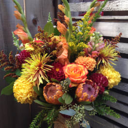 Colorful bouquet with orange roses and yellow chrysanthemums in a burlap-wrapped vase