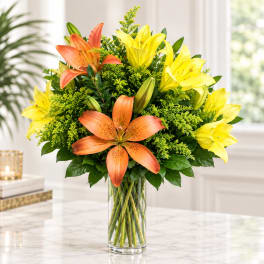 Orange and yellow lilies arranged in a clear glass vase
