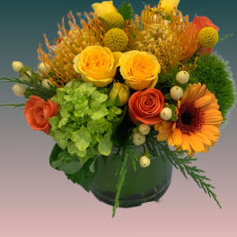 Bright mixed bouquet in a dark glass vase with yellow and orange blooms