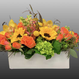 Bright mixed flower arrangement in a white rectangular container