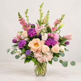 Mixed pink and purple flowers arranged in a clear glass vase