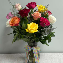 Mixed roses in a clear glass vase with a striped ribbon