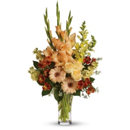Tall arrangement of peach roses, gerberas and mixed flowers in a clear glass vase