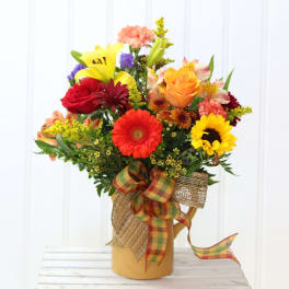 Colorful mixed bouquet in a tan pitcher with a plaid ribbon