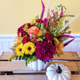 Colorful flower arrangement in a white pumpkin-shaped vase with a small white pumpkin decor piece nearby.