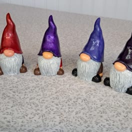 Four painted gnome figurines with tall hats on a patterned surface
