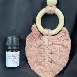 Macrame wall hanging and a small essential oil bottle on dark fabric