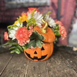 Halloween pumpkin container with mixed flowers and a jack-o'-lantern face