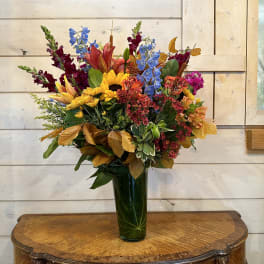 Colorful mixed bouquet in a tall green glass vase