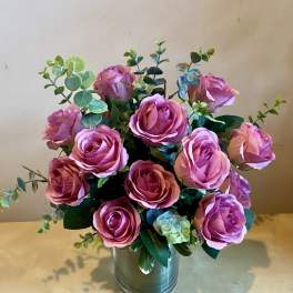 Pink roses arranged in a metal vase with eucalyptus