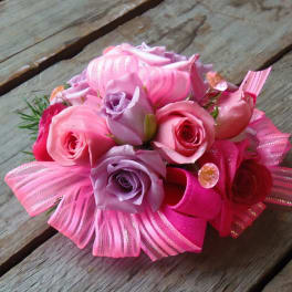 Pink and lavender rose bouquet with ribbon accents on a wooden surface