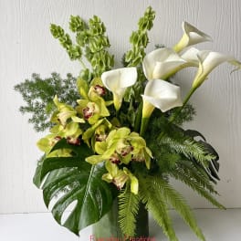 White calla lilies and green orchids in a glass vase
